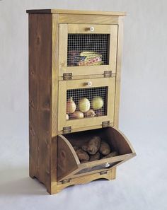 a wooden cabinet with three compartments filled with fruits and vegetables, including an egg carton