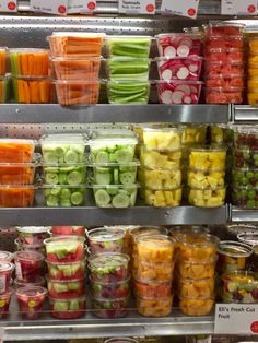 many different types of fruits and vegetables are on display in a grocery store, including apples, cucumbers, celery, carrots, watermelon, and more