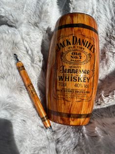 a pen and wooden barrel sitting on top of a white furnishing area next to a bottle of jack daniels whiskey