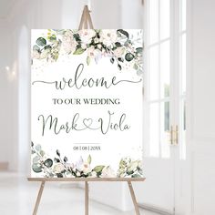 an easel with a sign that says welcome to our wedding, and flowers on it