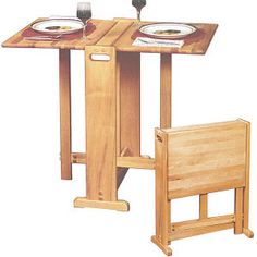 a wooden table with two plates on it and one chair next to it, in front of a white background