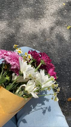 a bouquet of flowers sitting on top of someone's lap in the sun,