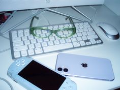 an apple computer, keyboard and glasses on a white desk with the phone next to it