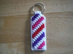 a crocheted keychain with a red, purple and white stripe on it