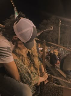 a man and woman sitting next to each other in front of a crowd at night