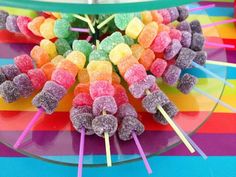 there are many different colored lollipops on the glass platter with sticks