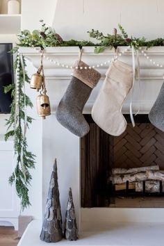 stockings hanging from a mantel with christmas decorations