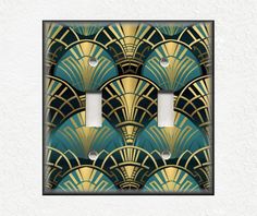 an art deco light switch plate cover in gold and teal with fan design on it