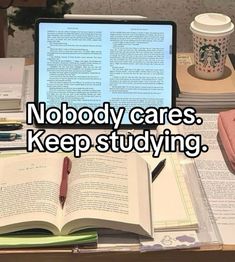 an open laptop computer sitting on top of a desk next to books and a cup