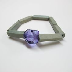 a bracelet made out of concrete blocks with a purple glass bead