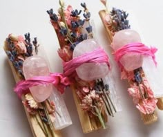 three wooden sticks with flowers tied to them on top of a white table next to each other