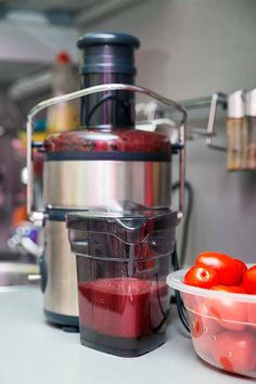 a bowl of tomatoes next to a juicer