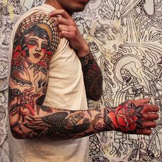 a man with many tattoos on his arm and arms is standing in front of a wall