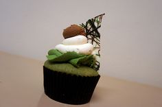 a cupcake with green icing and white frosting on top sitting on a table