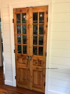 two wooden doors with glass inserts in a white wall and wood flooring on the side