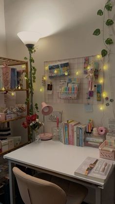 a white desk topped with lots of books next to a wall covered in plants and lights