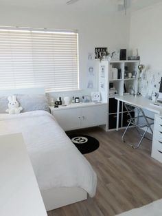 a bedroom with white walls and wooden floors has a bed, desk, and shelves