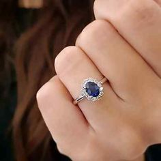 a close up of a person wearing a ring with a blue stone in the middle