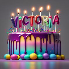 a birthday cake with lit candles and the word victoria on it is surrounded by colorful icing