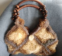 a crocheted purse with wooden beads hanging from it's handle on the back of a chair