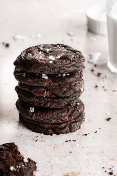 a stack of chocolate cookies sitting on top of a table next to a glass of milk