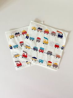 two napkins with vehicles on them sitting next to each other in front of a white background