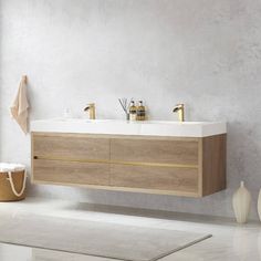 a bathroom vanity with two sinks and gold faucets on the countertop next to a white rug