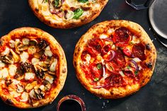 three pizzas sitting on top of a black table