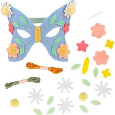 a blue mask with flowers on it next to cut outs and paper flowers in the background