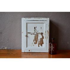 an old white frame sitting on top of a wooden table next to a brown bottle