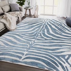 a blue and white rug with zebra print on the floor in front of a couch