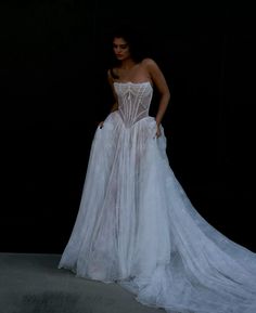 a woman in a white dress standing on a black background with her back to the camera