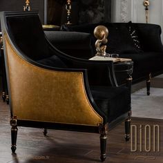 a black couch with gold accents and a table in front of it on a hard wood floor