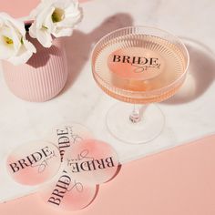 two bride stickers sitting next to a wine glass on a table with white flowers