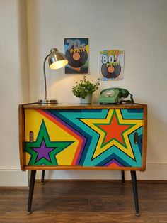 a brightly colored cabinet with two pictures on the wall and a lamp next to it