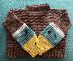 a knitted sweater with a bird on the front and two buttons at the back