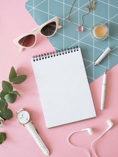 a notepad, pen, watch and sunglasses on a pink background