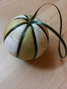 an ornament on a wooden table with a green ribbon tied around the top