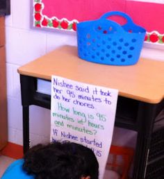 a young child sitting on a blue chair in front of a desk with a sign