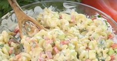 a bowl full of macaroni salad with a wooden spoon