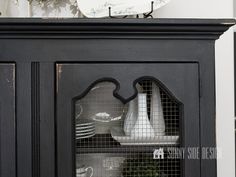 a black china cabinet with white dishes on it