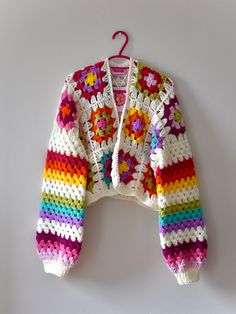 a colorful crocheted jacket hanging on a wall