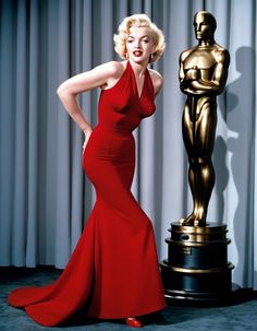 a woman in a red dress standing next to an oscar statue and posing for the camera