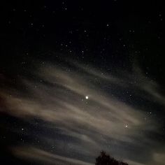 the night sky is full of stars and clouds, as well as some trees in the foreground