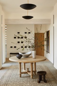 a round table with two black vases on top of it in a living room