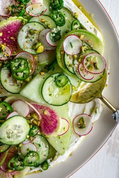 a white plate topped with cucumbers, radishes and other veggies