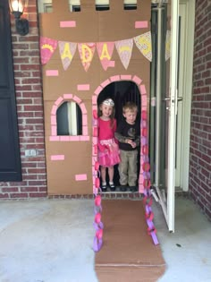 two young children standing in a cardboard castle made to look like they are having fun