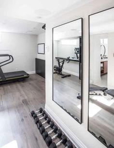 an exercise room with mirrors and treadmills on the wall in front of it