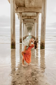 a man and woman kissing under a pier