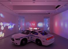 two police cars parked next to each other in a room with colorful lights on the walls